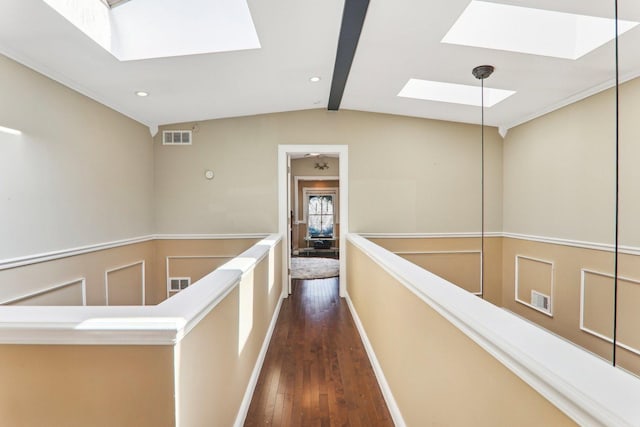 hall with visible vents, an upstairs landing, wainscoting, a decorative wall, and dark wood-style flooring