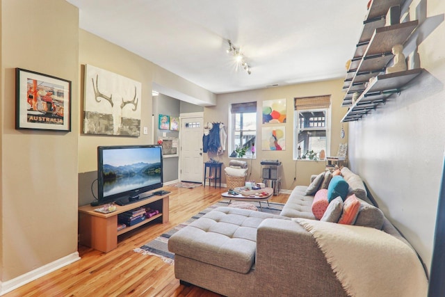 living area with track lighting, baseboards, and wood finished floors