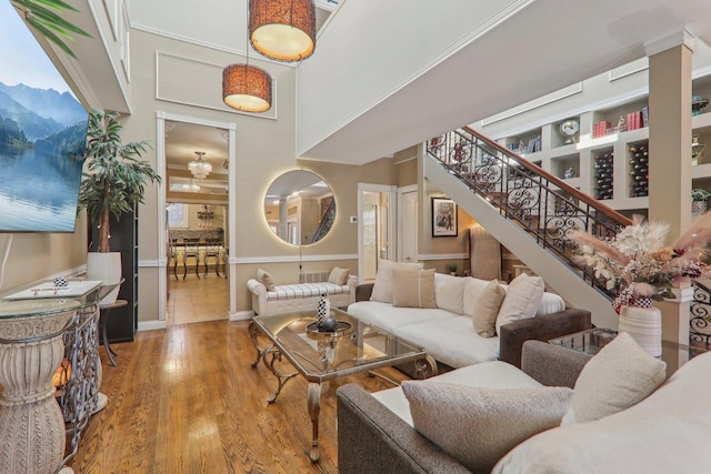 living room featuring stairs, wood finished floors, baseboards, and a towering ceiling