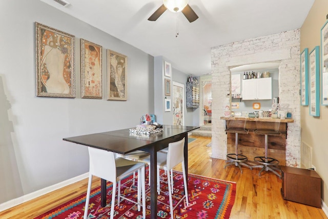 dining room featuring baseboards, a ceiling fan, and light wood finished floors