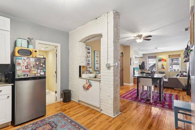 kitchen with visible vents, white cabinetry, freestanding refrigerator, light wood-style floors, and light countertops