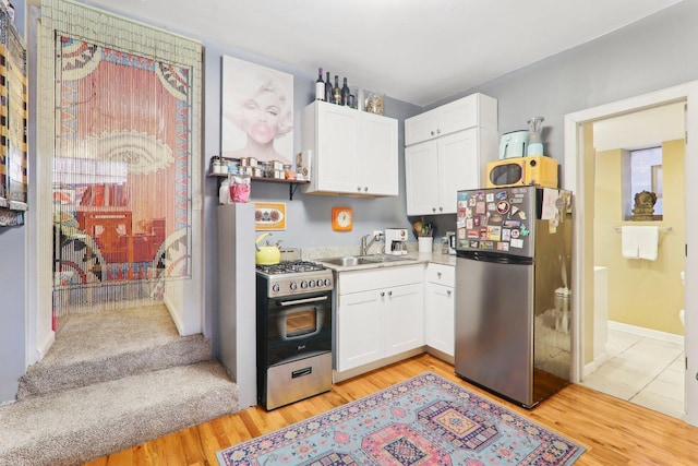 kitchen with light wood finished floors, white cabinetry, stainless steel appliances, and light countertops