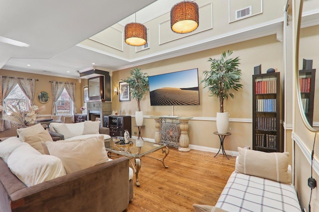 living room featuring wood finished floors, baseboards, visible vents, recessed lighting, and a fireplace