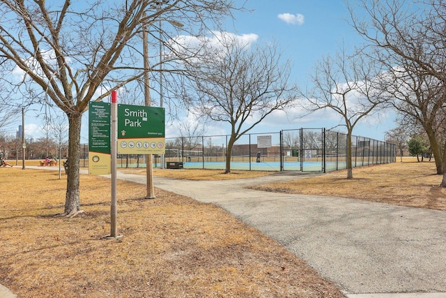 surrounding community featuring a tennis court, a gate, fence, and driveway