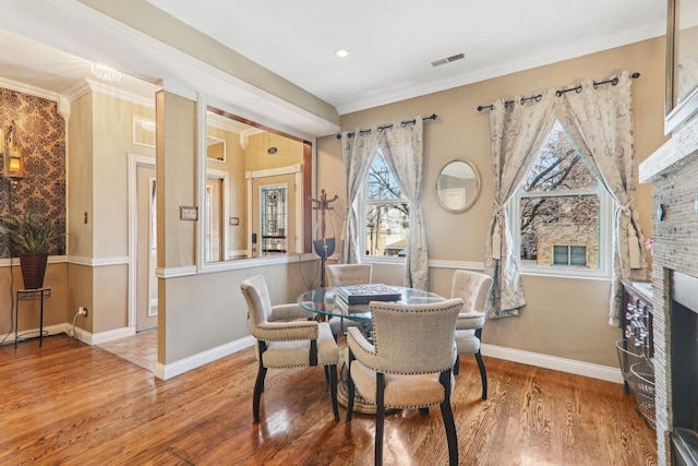 dining room featuring ornamental molding, wood finished floors, visible vents, and baseboards