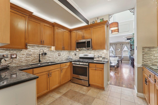 kitchen with brown cabinetry, backsplash, appliances with stainless steel finishes, and a sink