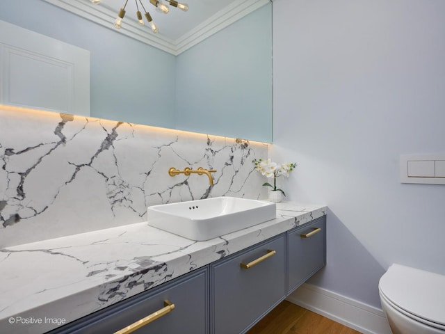 bathroom featuring vanity, wood finished floors, an inviting chandelier, toilet, and backsplash