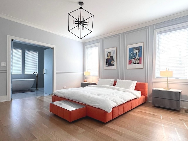 bedroom featuring light wood-type flooring, baseboards, a notable chandelier, and crown molding