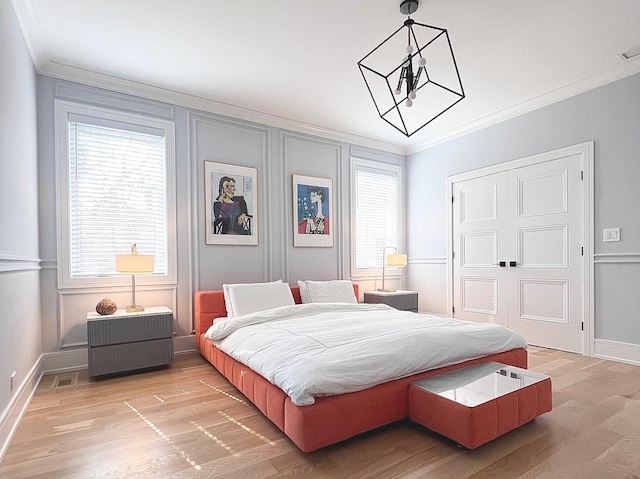 bedroom with crown molding, light wood-style flooring, and multiple windows