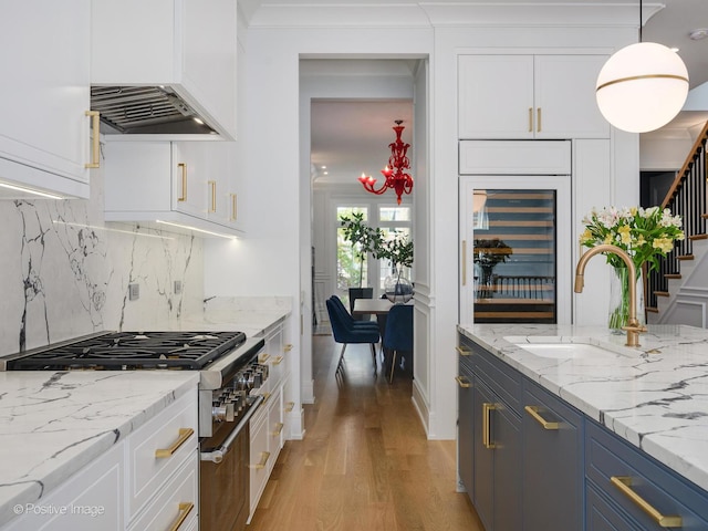 kitchen featuring a sink, light wood-type flooring, beverage cooler, and white cabinets