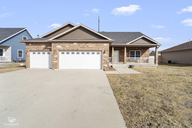 view of front of home featuring a garage, brick siding, covered porch, and driveway