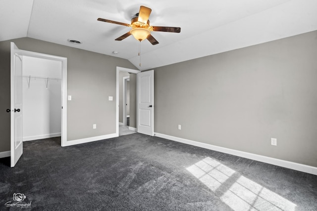 unfurnished bedroom with lofted ceiling, visible vents, baseboards, and dark carpet