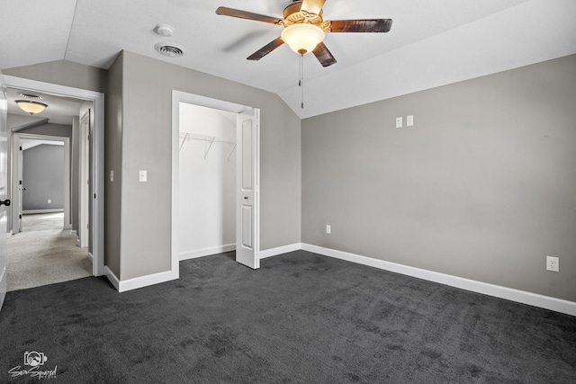 unfurnished bedroom with visible vents, baseboards, dark carpet, and vaulted ceiling