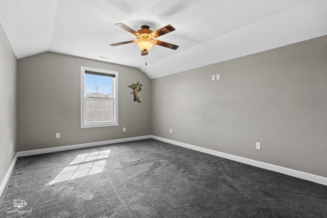 interior space with vaulted ceiling, a ceiling fan, baseboards, and dark carpet