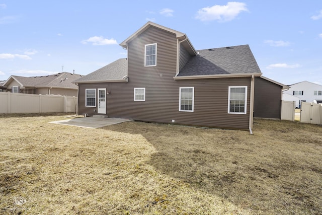 back of house with a yard, fence, a shingled roof, and a patio area