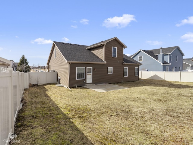 rear view of property featuring a patio, a lawn, roof with shingles, and a fenced backyard