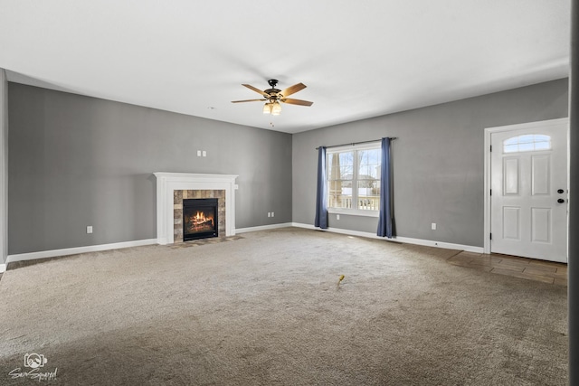 unfurnished living room featuring a tiled fireplace, baseboards, a ceiling fan, and carpet