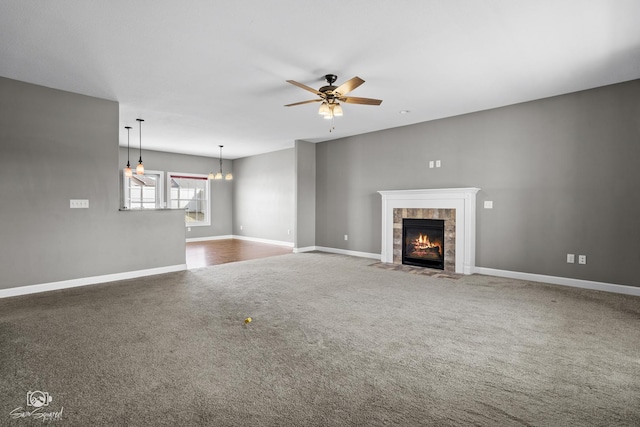 unfurnished living room with a fireplace, baseboards, a ceiling fan, and carpet floors