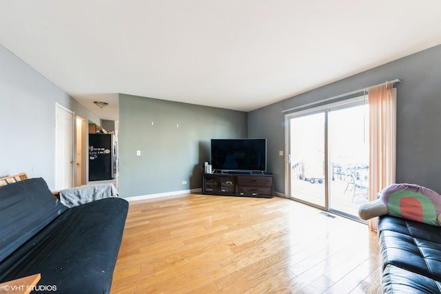 living room featuring visible vents, baseboards, and light wood-style flooring