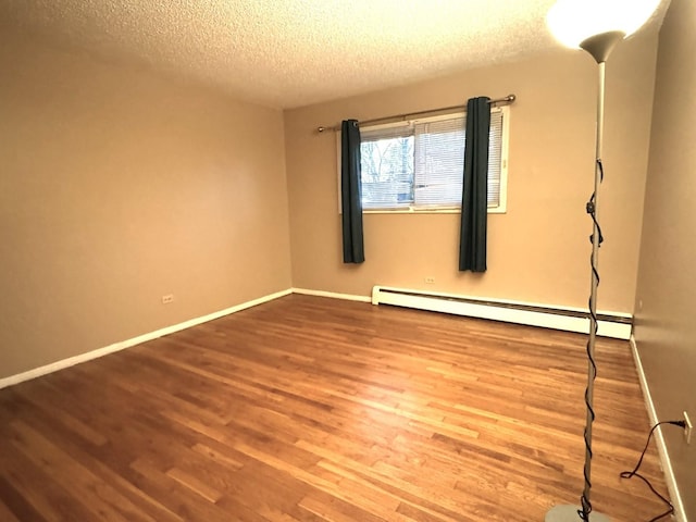 unfurnished room featuring a textured ceiling, wood finished floors, baseboards, and a baseboard radiator