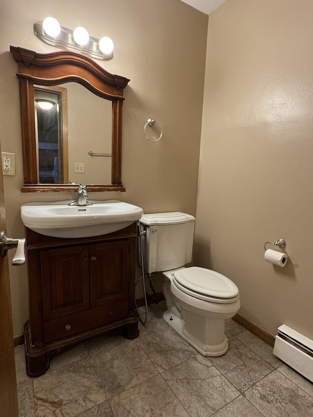 half bathroom featuring vanity, toilet, baseboards, and a baseboard radiator