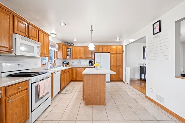 kitchen with visible vents, a kitchen island, light countertops, white appliances, and a sink