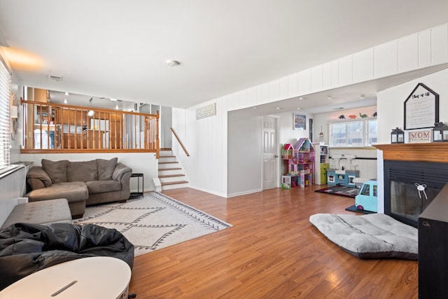 living room with visible vents, baseboards, stairs, wood finished floors, and a glass covered fireplace