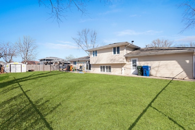 back of house featuring an outbuilding, fence, a patio area, a storage shed, and a lawn