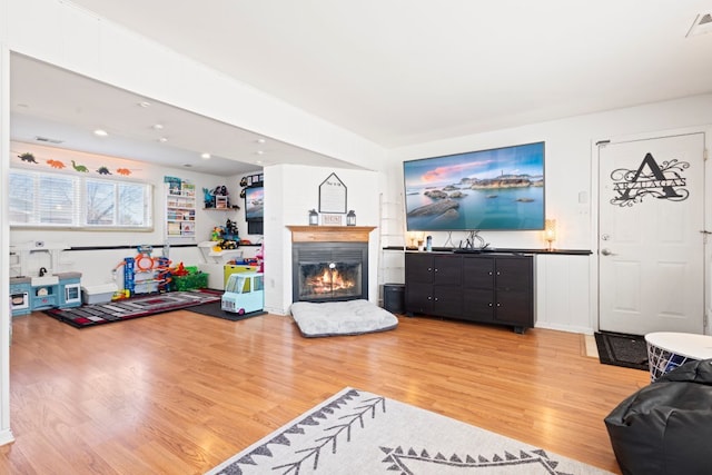 living room featuring a glass covered fireplace and light wood finished floors