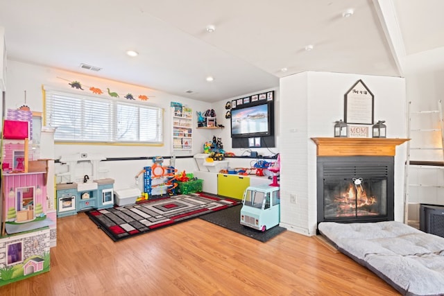 recreation room featuring a glass covered fireplace, recessed lighting, wood finished floors, and visible vents