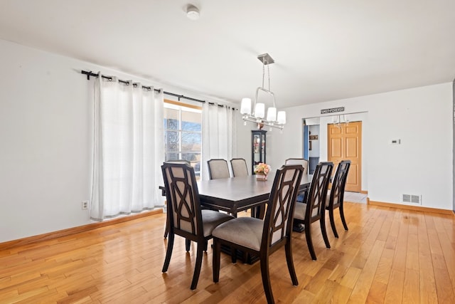 dining area with visible vents, baseboards, an inviting chandelier, and light wood finished floors