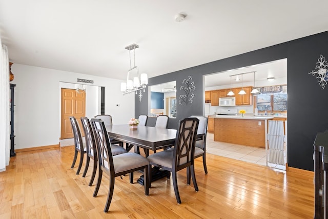 dining area with a chandelier, baseboards, and light wood-style floors