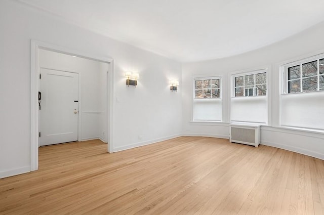 unfurnished room with light wood-type flooring, radiator heating unit, and baseboards