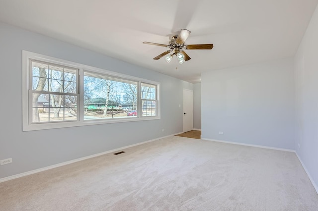 spare room featuring light carpet, visible vents, ceiling fan, and baseboards