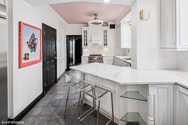 kitchen featuring premium appliances, backsplash, a peninsula, and white cabinetry