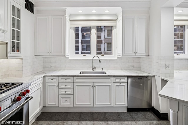 kitchen featuring a sink, tasteful backsplash, appliances with stainless steel finishes, white cabinets, and light stone countertops