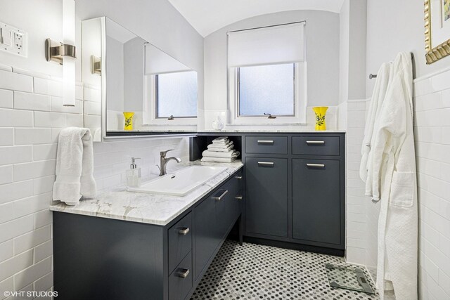 full bathroom with vanity, tile walls, and wainscoting