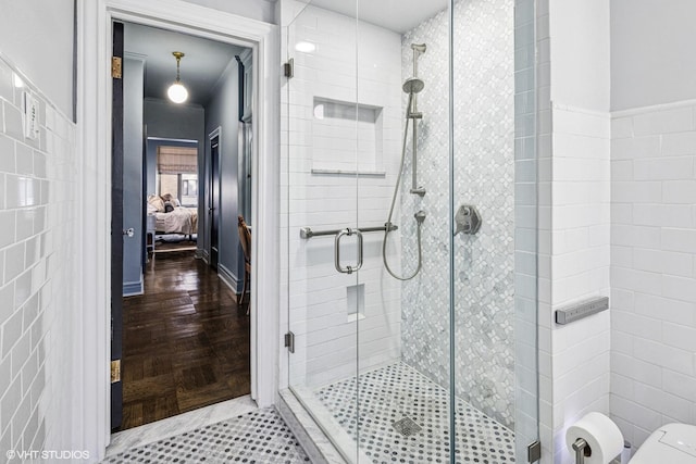 ensuite bathroom with connected bathroom, tile walls, a shower stall, and toilet