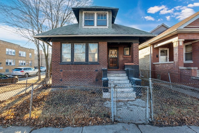 bungalow-style house with brick siding, roof with shingles, a fenced front yard, and a gate