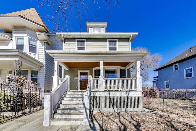 american foursquare style home featuring a porch and fence