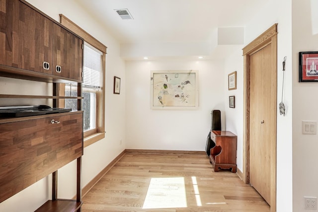 corridor featuring light wood-style flooring, baseboards, and visible vents