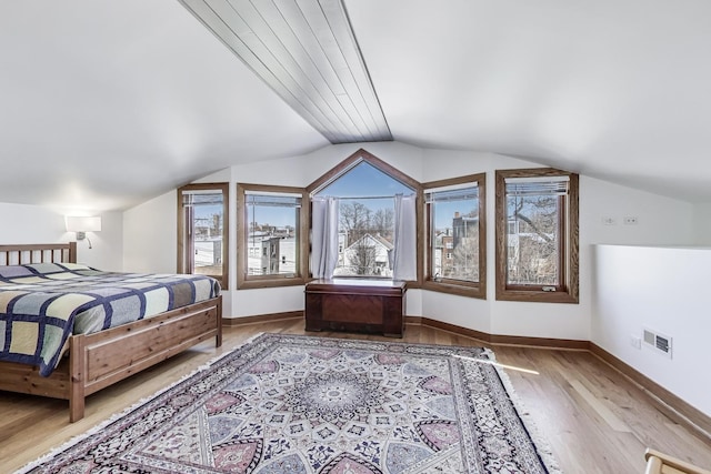 bedroom featuring vaulted ceiling, wood finished floors, visible vents, and baseboards