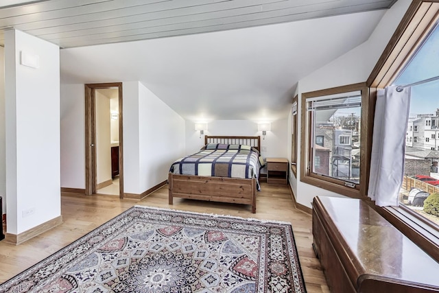 bedroom featuring baseboards, lofted ceiling, and light wood finished floors