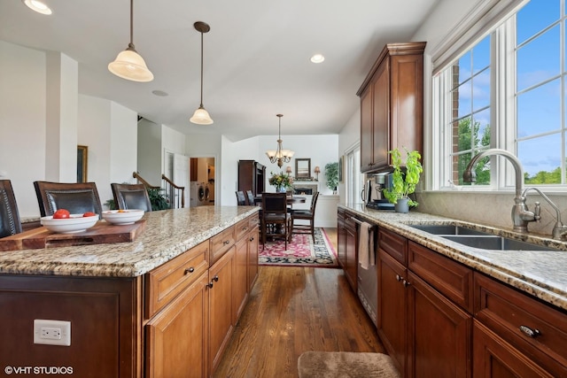 kitchen with light stone countertops, dark wood-style flooring, a sink, hanging light fixtures, and dishwasher