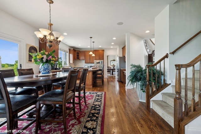 dining space featuring a notable chandelier, recessed lighting, stairs, and dark wood-style flooring