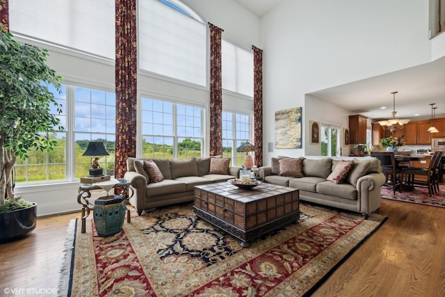 living area with a high ceiling, an inviting chandelier, and wood finished floors