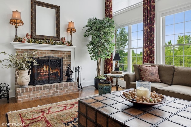 living area featuring a wealth of natural light, baseboards, wood finished floors, and a fireplace