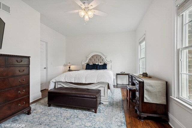 bedroom featuring a ceiling fan, wood finished floors, visible vents, and baseboards