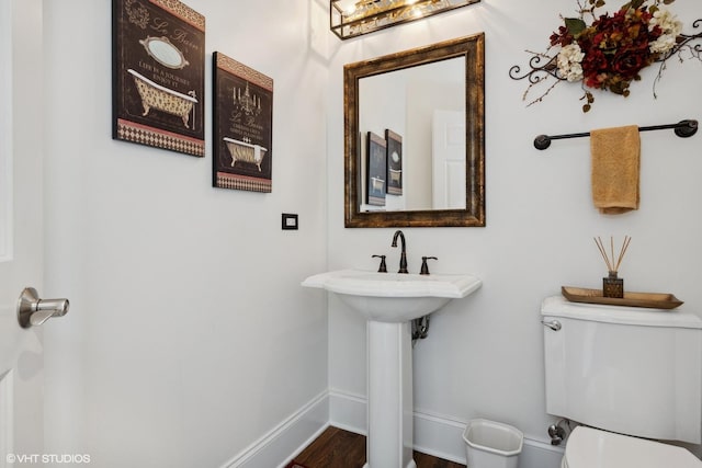 bathroom with toilet, wood finished floors, and baseboards