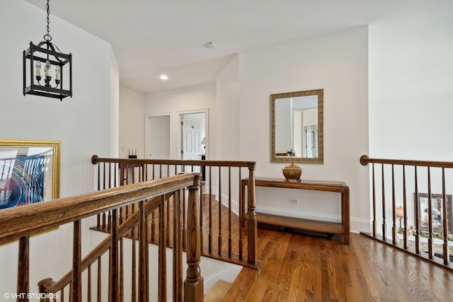 corridor with wood finished floors, recessed lighting, an upstairs landing, and baseboards